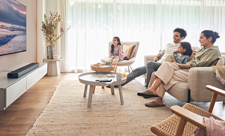 Una familia viendo un televisor con una barra de sonido debajo